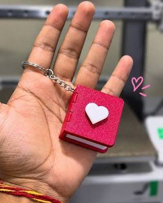 Small red book keychain held in an open palm